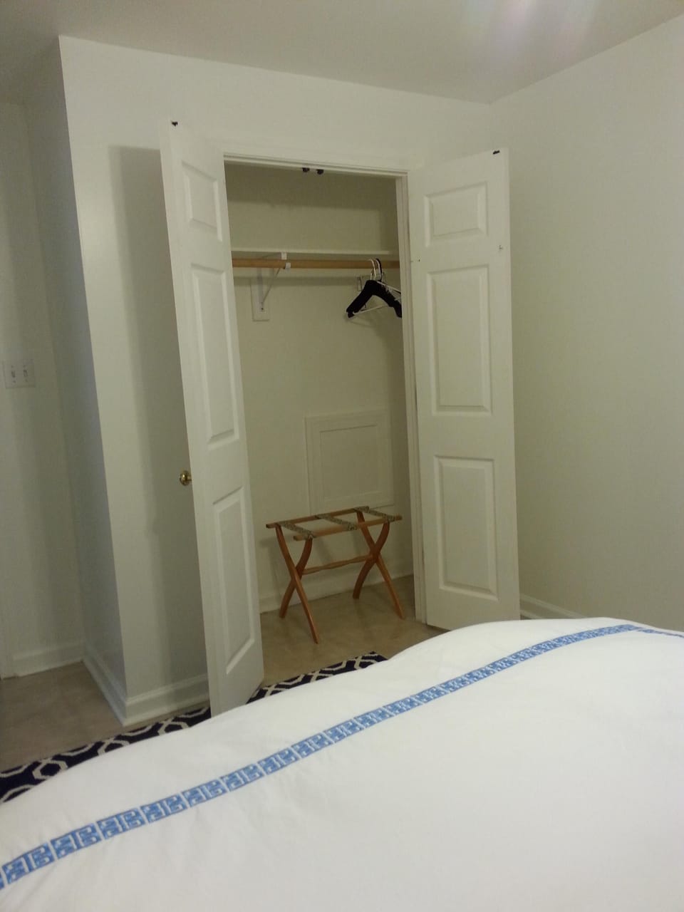 open closet with hangers and luggage rack.