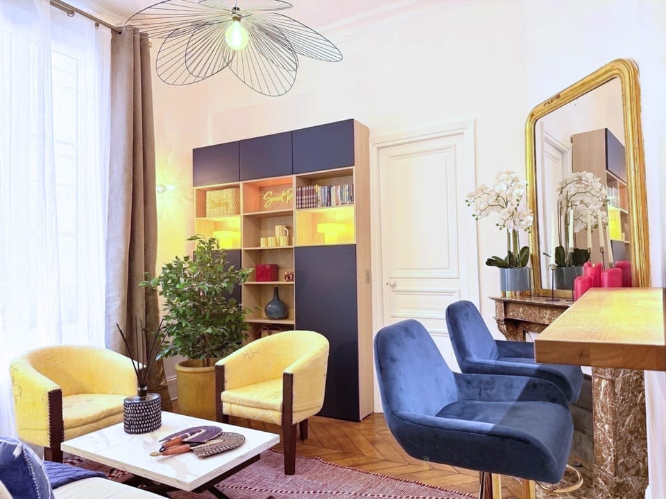SWEET PARIS – Vue du salon avec ses deux fauteuils, sa bibliothèque, son bar et sa table basse