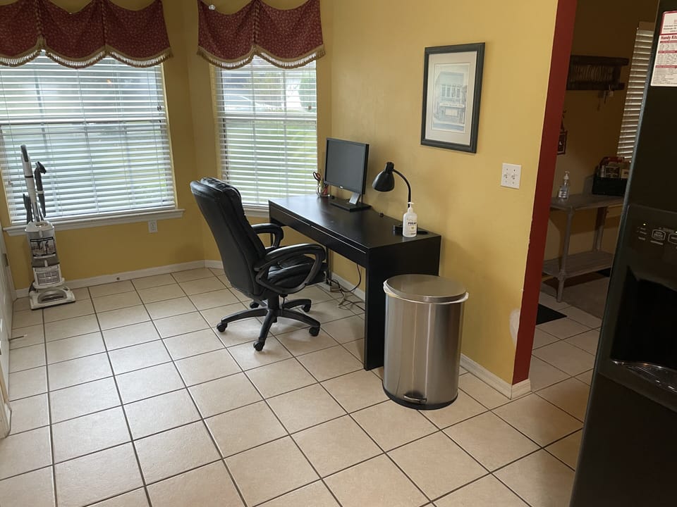 Office area with desk, office chair, lamp, monitor and miscellaneous supplies