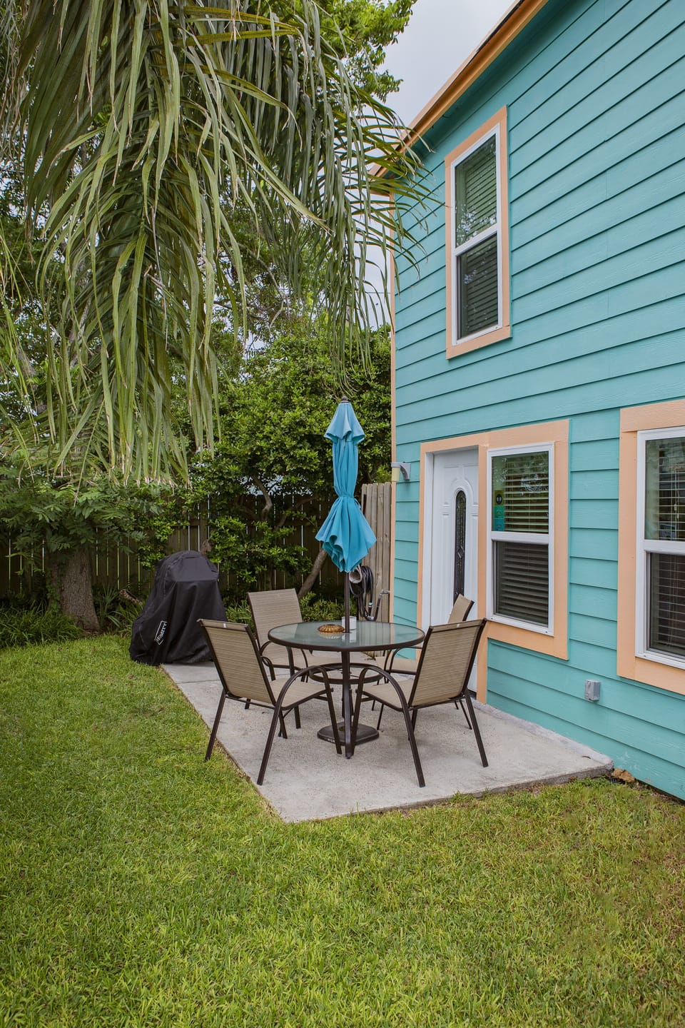 Small private yard with patio with table, chairs, shade umbrella.