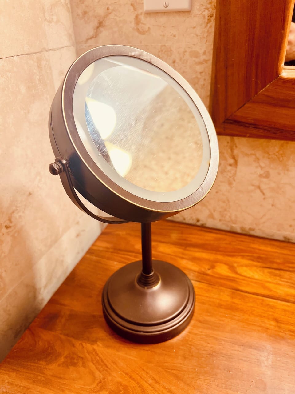 Luxury bathroom amenity featuring a lighted makeup mirror on a warm wood vanity.