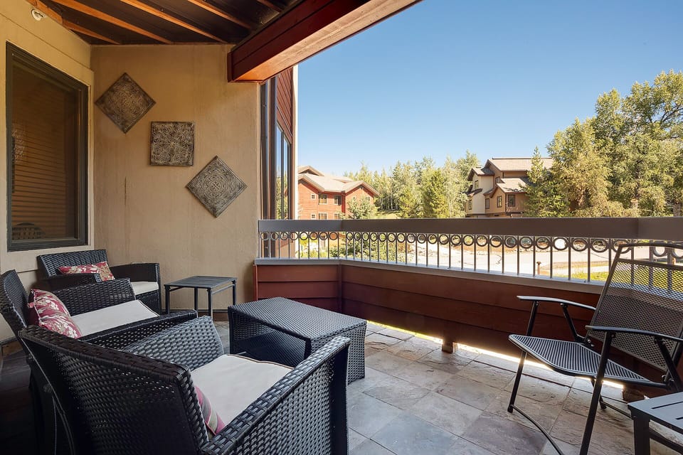 Step onto your private balcony where comfortable seating awaits beneath exposed wooden beams, offering peaceful views of the tree-lined neighborhood.
