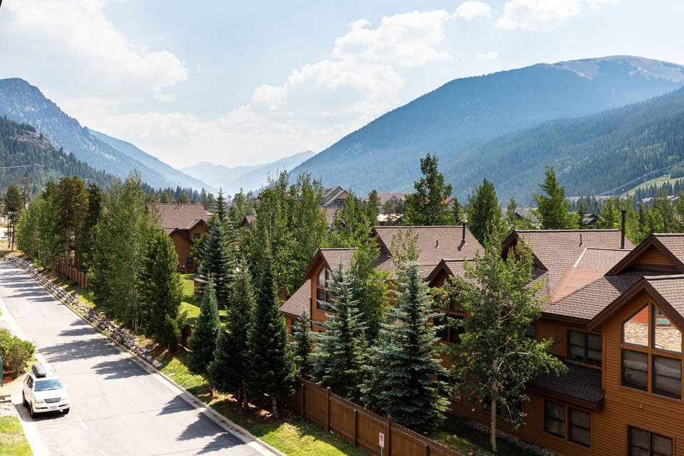 Mountain-view residential community nestled in a scenic valley with towering peaks and alpine forest surroundings.