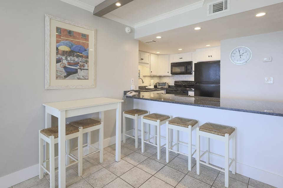 This kitchen features sleek black appliances, granite countertops, and a cozy breakfast bar for casual dining