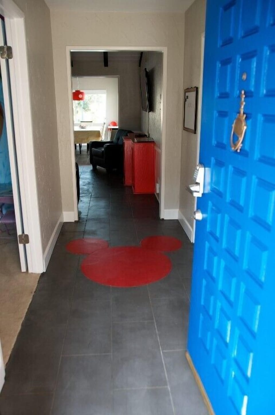- Welcoming entryway with bold blue door making a cheerful first impression   - Unique Mickey shaped floor design adding fun Disney details   - Open hallway leading to living and dining areas inside