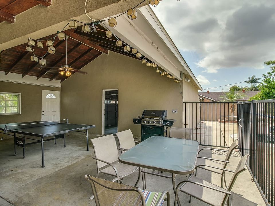 - Covered patio with dining table and barbecue grill   - String lights create ambiance for evening meals   - Fun space with ping pong and outdoor relaxation