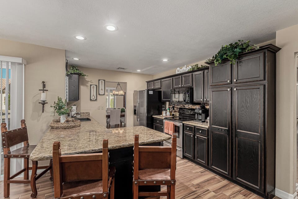 Kitchen features stainless appliances and eat at granite bar .