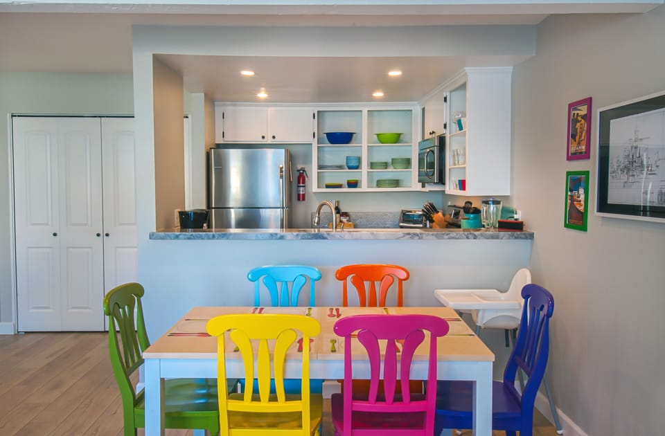 - Kitchen with stainless steel appliances open shelving and colorful touches   - Dining area with rainbow chairs brings cheerful style to every family meal   - Airbnb optimized caption highlighting kitchen and dining space keywords