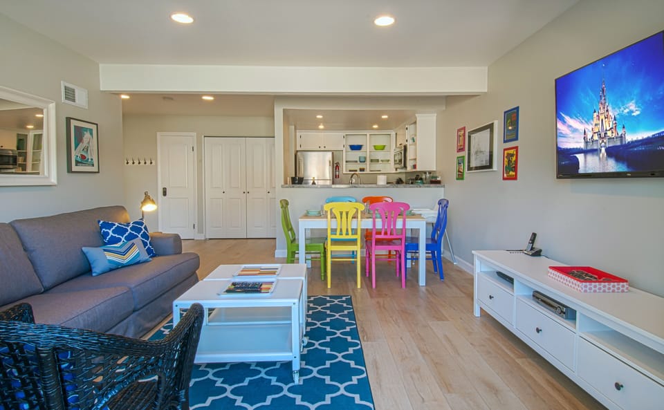 - Open floor plan features living room dining table and bright modern kitchen   - Colorful chairs and stainless steel appliances elevate guest meal times   - Airbnb optimized caption with family stay and open plan living keywords
