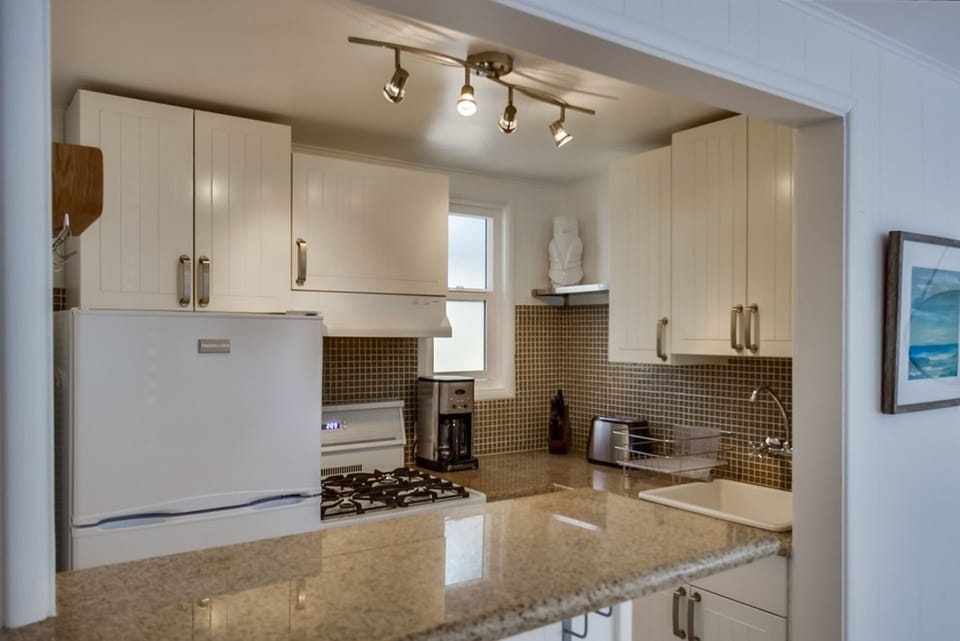 Fully stocked open kitchen with eat-in counter and barstools.