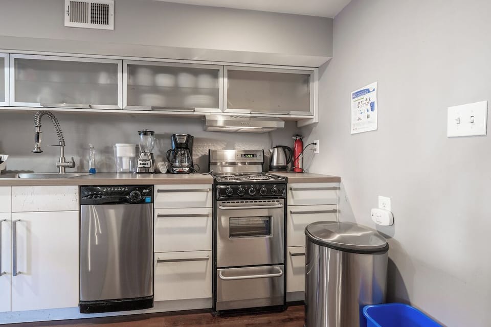 kitchen with oven/stove, dishwasher, garbage and recycling bins, and sink. 