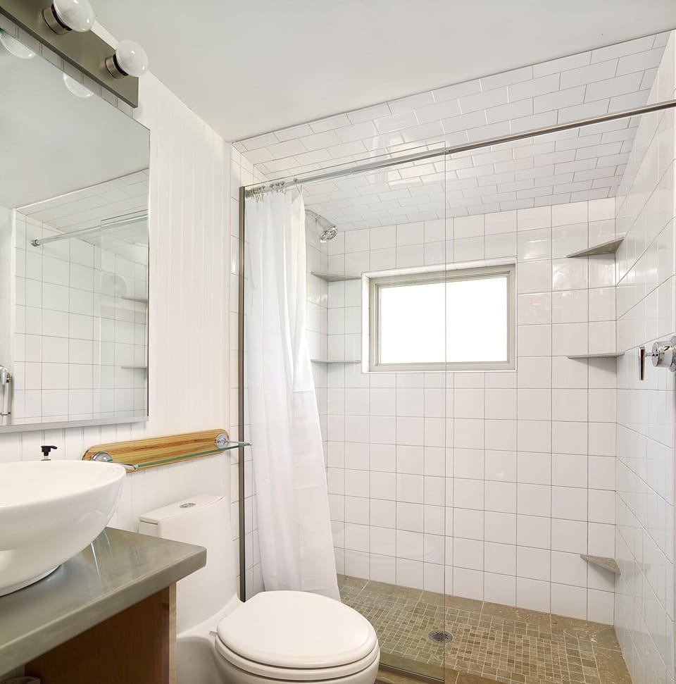 Clean modern tile, beautiful sink, natural light. We provide a starter supply of toilet paper, paper towels dishwasher pods, and conditioning shampoo and shower gel. 