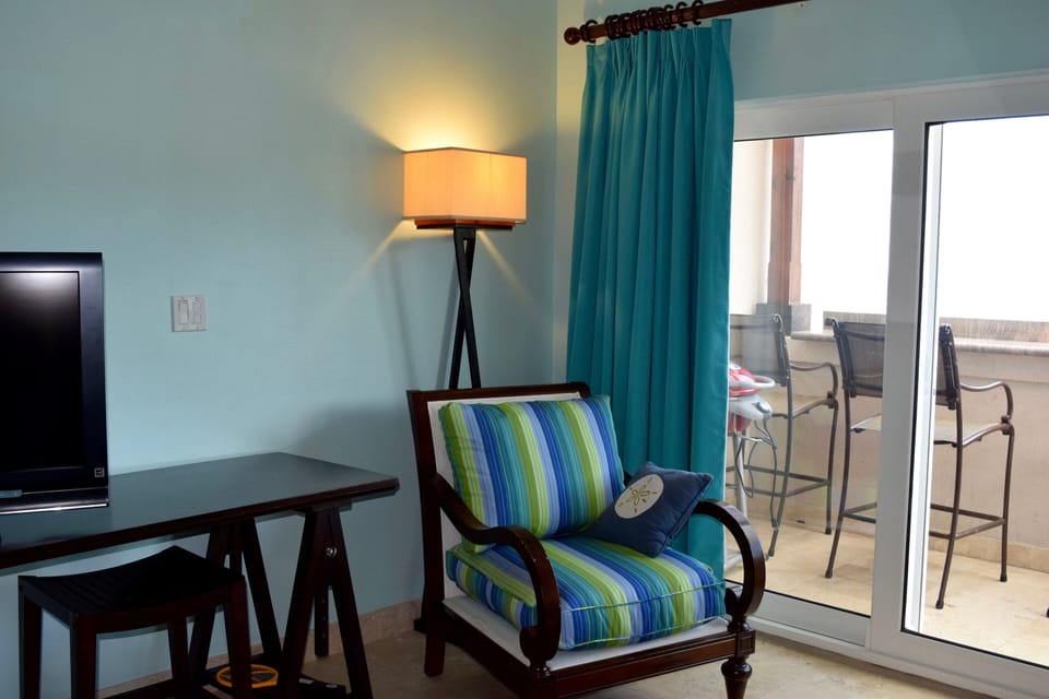 Side chair beside TV stand, balcony on right