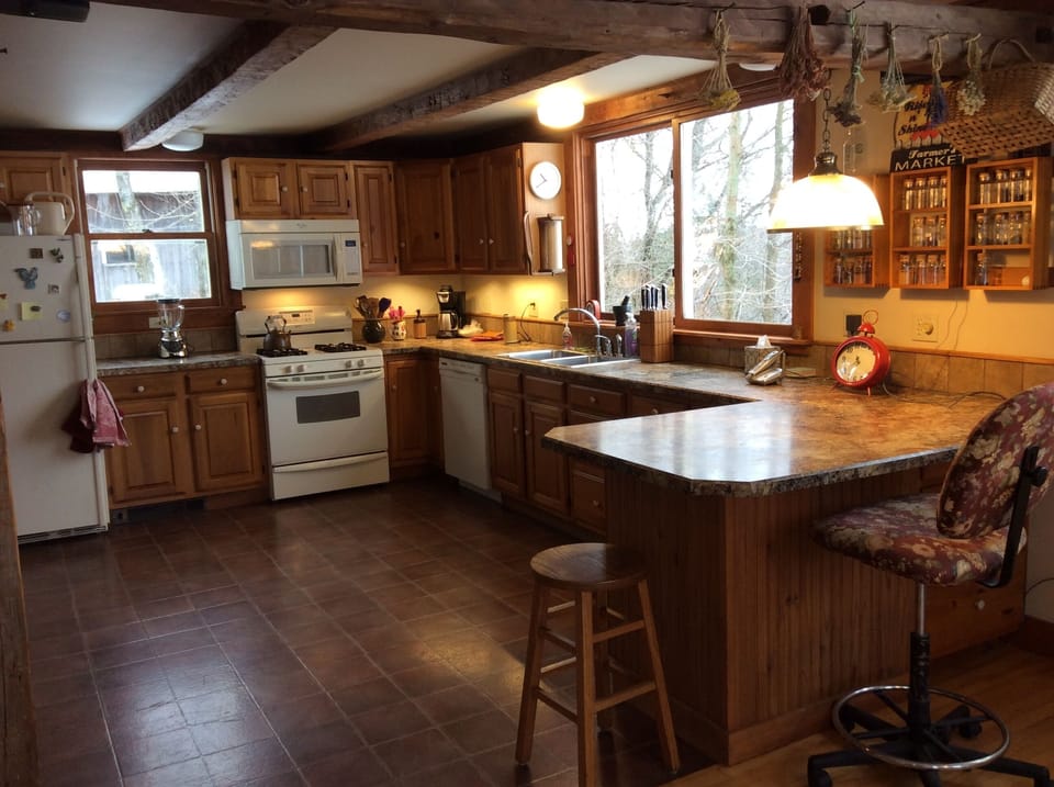 Partial view of kitchen, with spice racks, hanging dried herbs.
