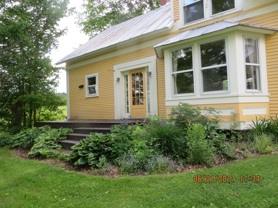 Front of house with flower gardens in very early summer.
