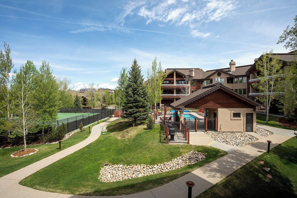 Property complex features landscaped grounds with tennis court, children's playground, and well-maintained walkways connecting the main buildings.