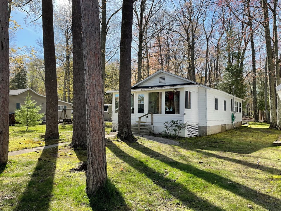 Front of house with 100 year old white pines lining the sidewalk. Lake view.