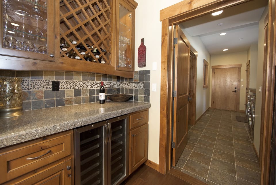 Cheers! Wine butler stocked w/stemless/stemmed wine glasses. Wine fridge below.