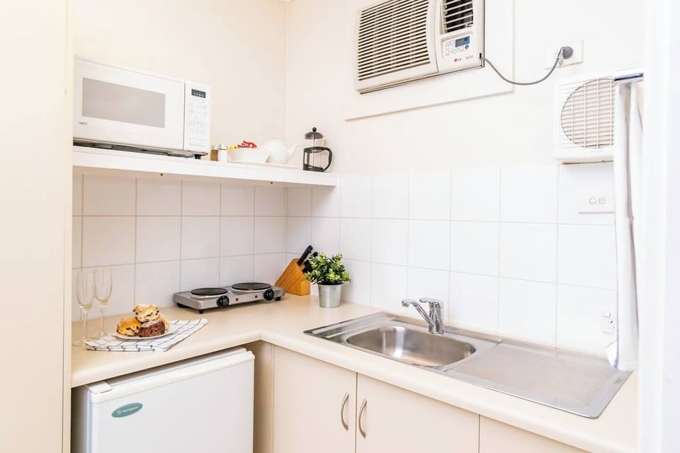 Kitchenette featuring mini fridge, microwave, hotplates and basic crockery/cookware.