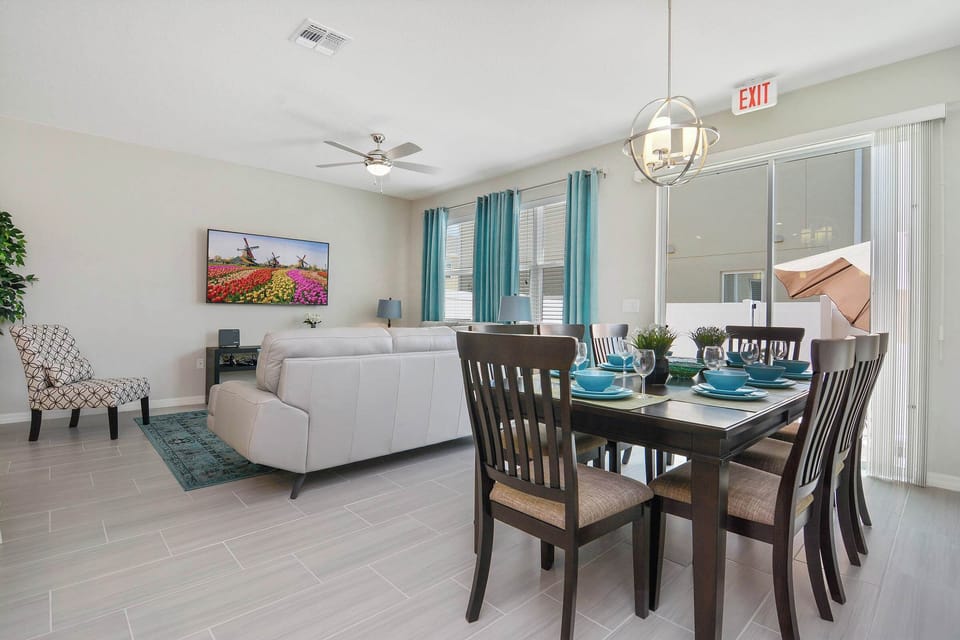Open-concept living and dining with teal accents, comfy leather sofas, large TV and dining for eight-airy, modern space that opens to a private patio.