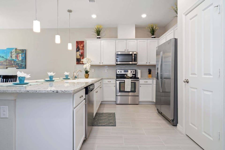 Whip up meals in the sleek modern kitchen with white cabinets, granite countertops, stainless-steel appliances and pendant lighting-bright, clean, and fully equipped for family cooking.