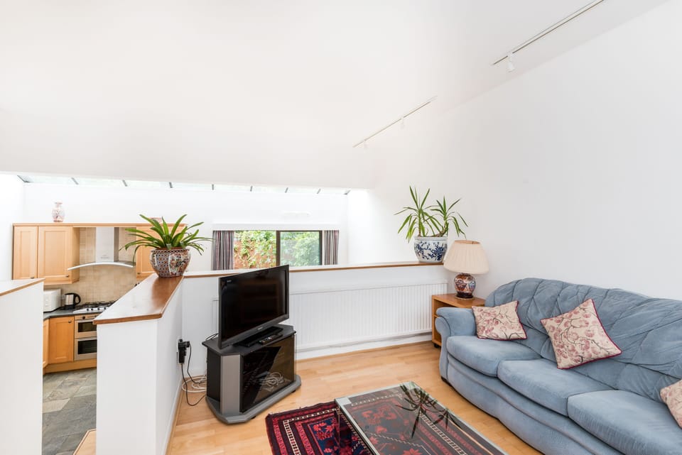 The TV area has a sociable layout from which steps lead down to the kitchen area