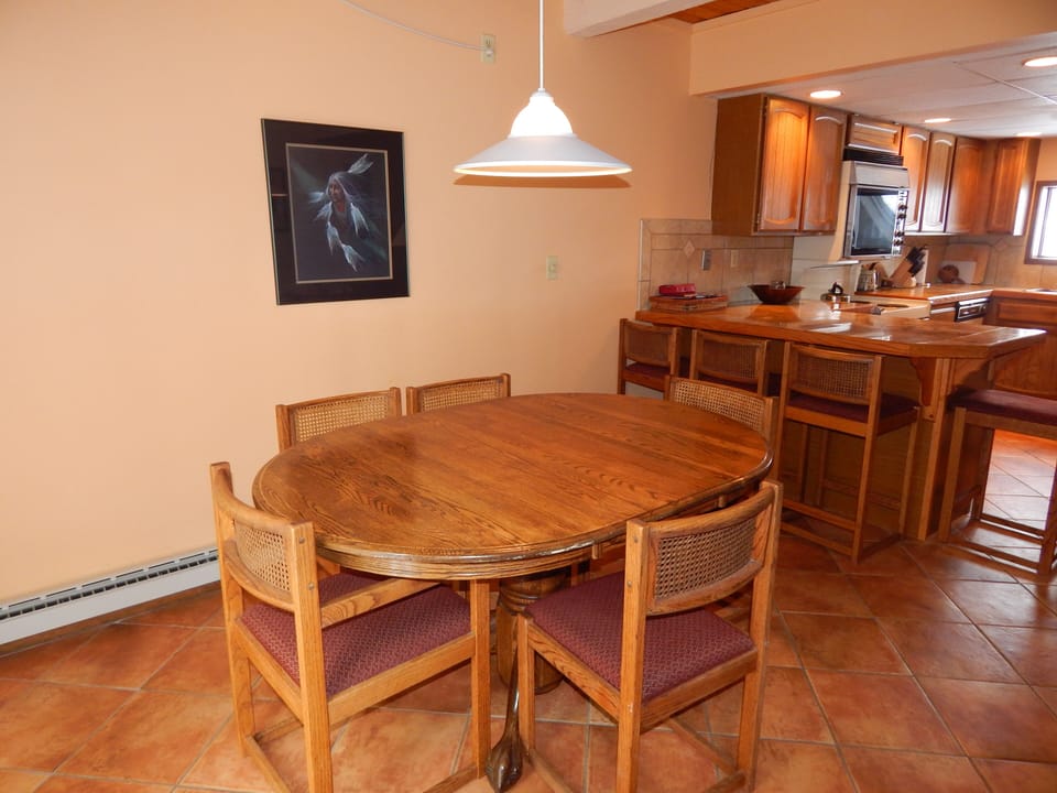 Gather around your warm wooden dining table for meals and conversations in this inviting open-concept space that flows seamlessly into your fully equipped kitchen.
