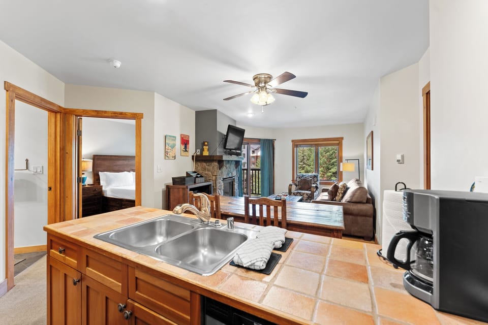 Enjoy your open-concept kitchen and living space with mountain views through the windows, comfortable seating around the fireplace, and all essentials for relaxing.