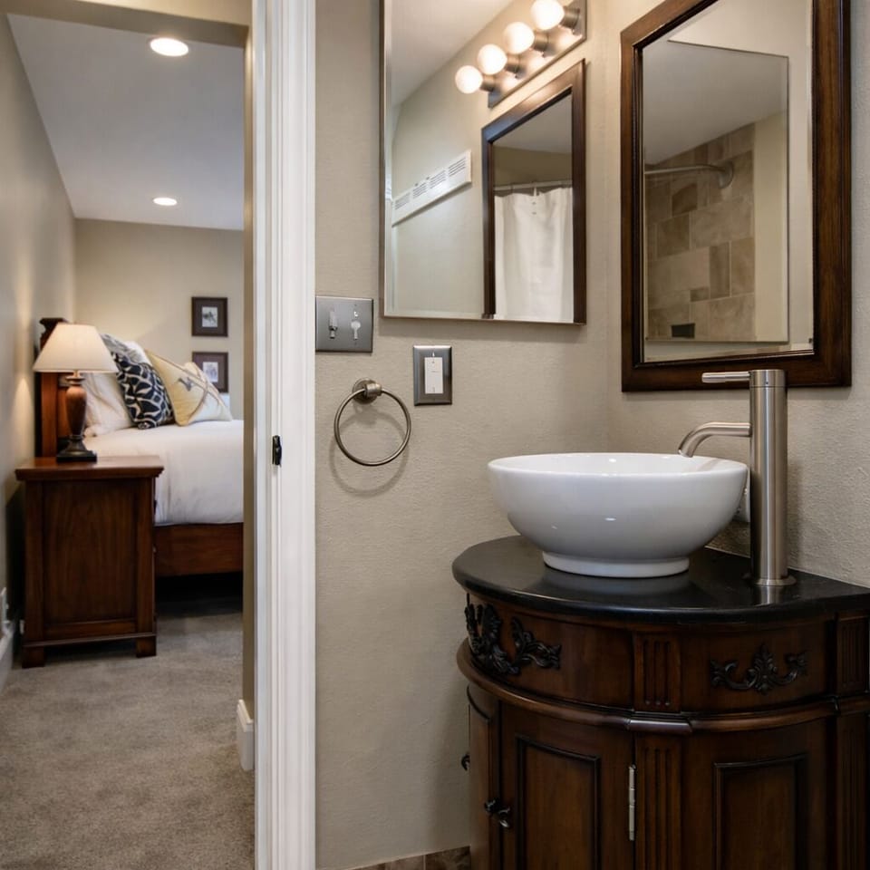 Your elegant bathroom features a beautiful vessel sink and stylish vanity, perfectly connecting to your comfortable bedroom space.