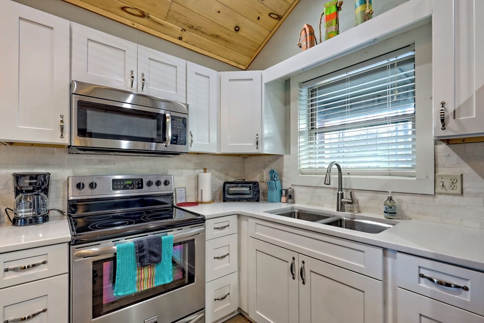 Bright modern kitchen with stainless appliances and warm wood ceiling