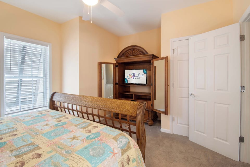 Your cozy bedroom features a comfortable bed and entertainment center with TV, perfect for unwinding after beach adventures.