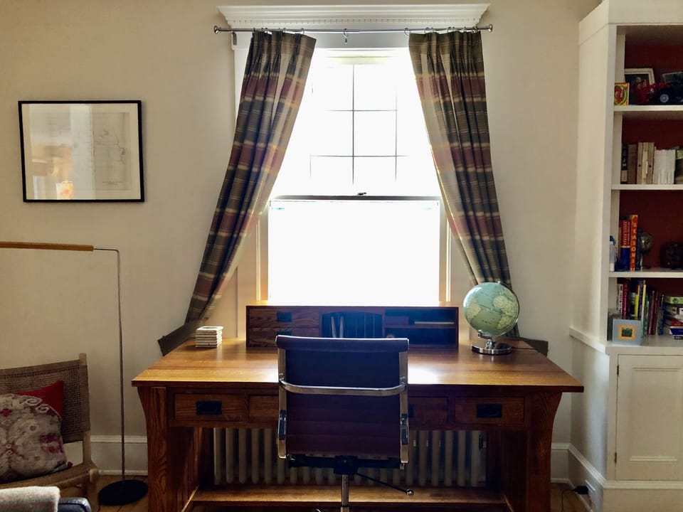 Writer's desk looks out on stone patio and trees.