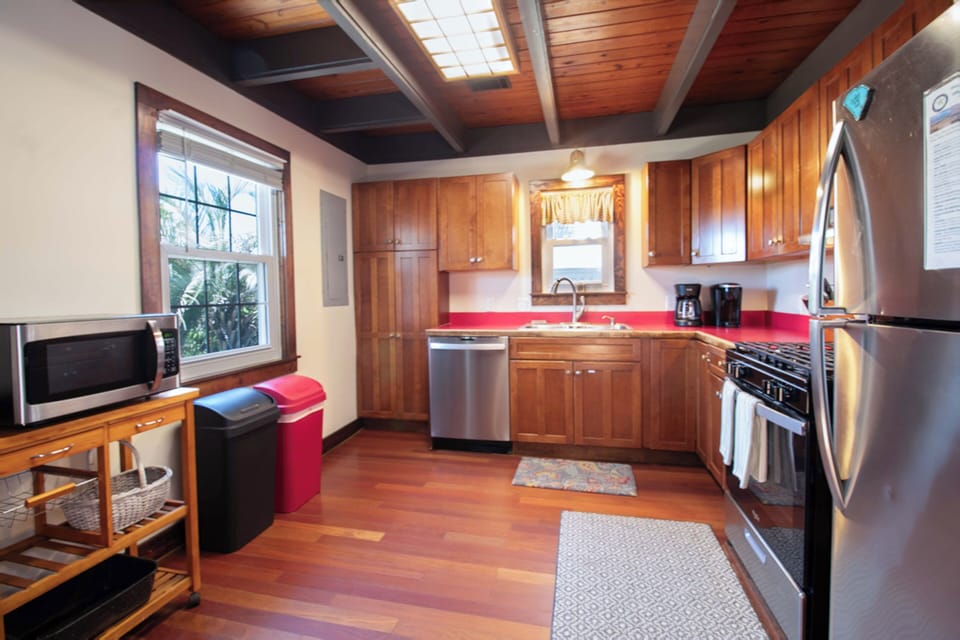 Your fully equipped kitchen features warm wood cabinetry, gleaming stainless appliances, and a cheerful pop of red—perfect for preparing home-cooked meals during your stay.