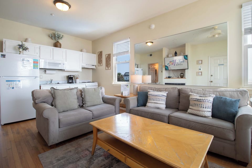 Settle into your inviting open-concept living area, where soft couches and coastal touches create a relaxed, homey vibe. Your fully equipped kitchen stands ready for easy meal prep, making you feel right at home from the moment you arrive.