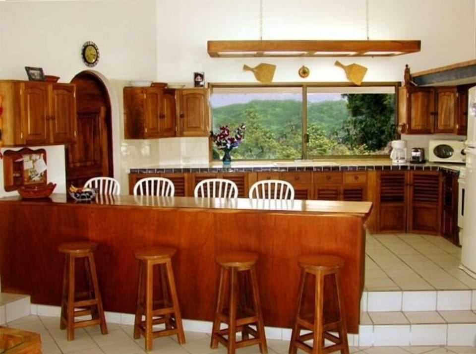 Roomy kitchen/custom built cabinets of native wood with two sided bar for dining