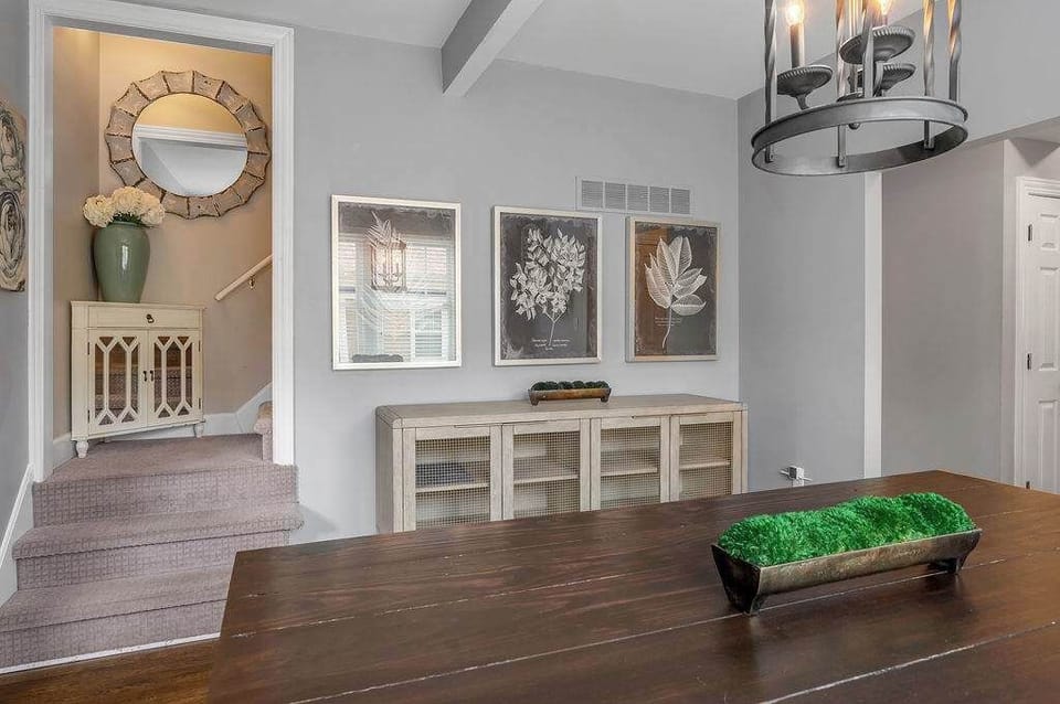 Dining space beside the staircase with a decorative buffet and round mirror.
