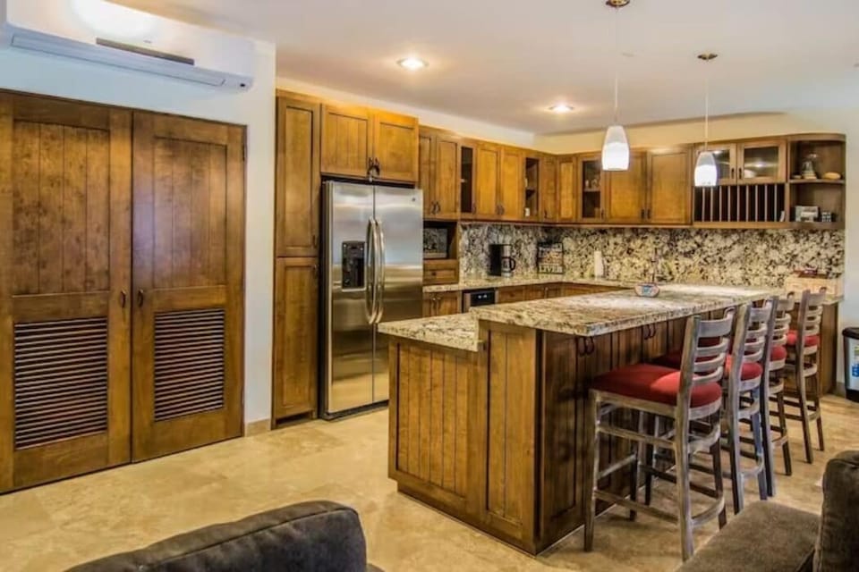 Kitchen has 4 high bar chairs at the well lighted bar.