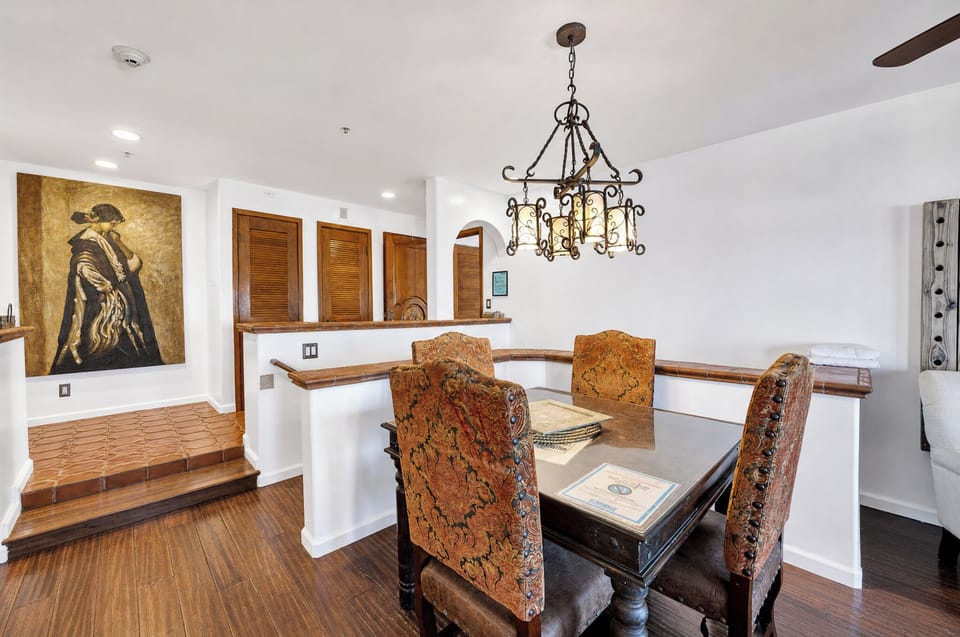 Gather around this stunning antique dining table beneath an ornate wrought-iron chandelier. The rich tapestry chairs and warm wood tones create an elegant space for your memorable meals together.