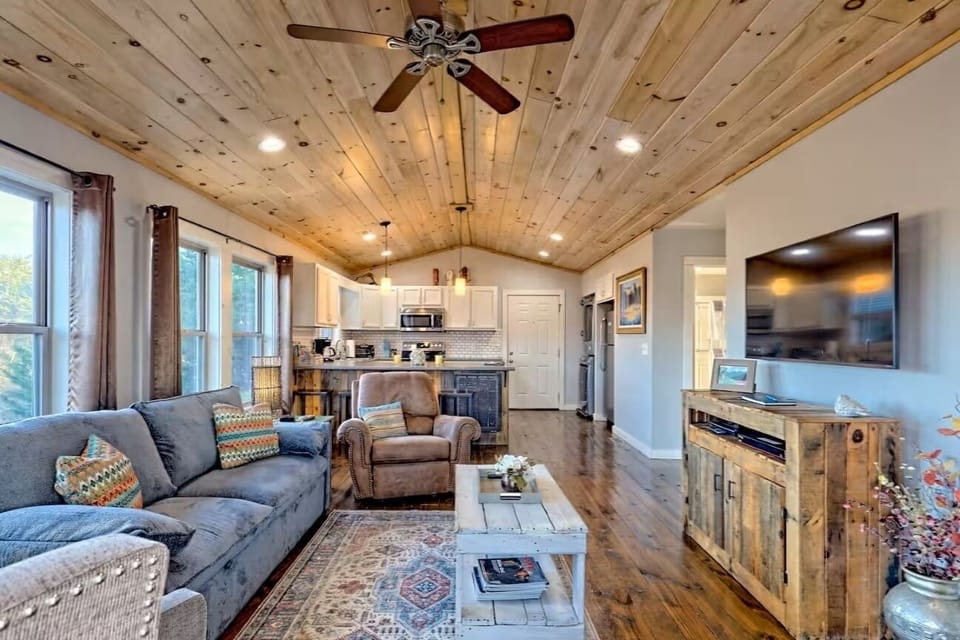 Cozy open-concept living room with vaulted wood ceilings and modern kitchen