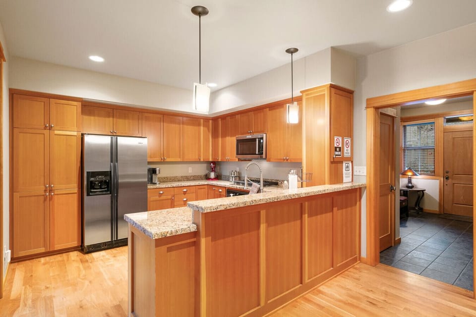 This spacious kitchen combines functionality and style with its stainless steel appliances, ample storage, and elegant lighting, offering a perfect setting for cooking and gathering.