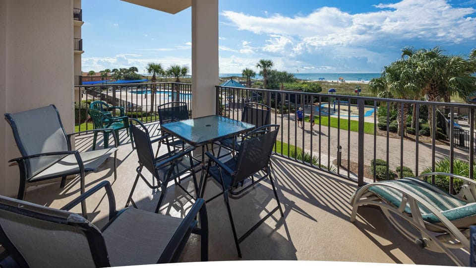 Relax on the balcony enjoying views of the pool and lush landscaping just steps from the beach
