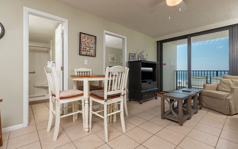 This cozy living area features a TV, a small dining table, and stunning beachfront views through large sliding glass doors