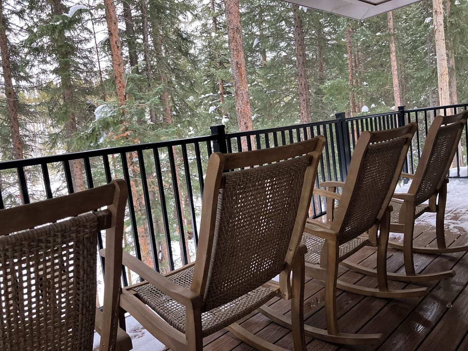Relax on your private balcony with comfy wicker rockers, watching snow dust the peaceful forest canopy beyond the railing.