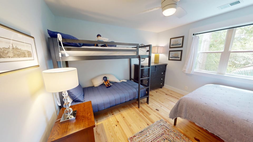Your kids will love this cheerful bedroom with a sturdy bunk bed, plus an extra full bed for flexible sleeping arrangements. Natural light pours through the window, illuminating warm wood floors and cozy furnishings.
