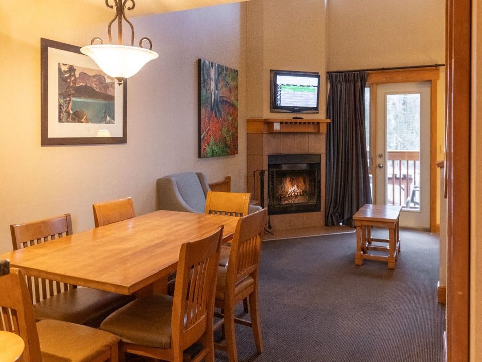 Enjoy meals at the spacious dining table or relax by the cozy fireplace in this warm and inviting living space.