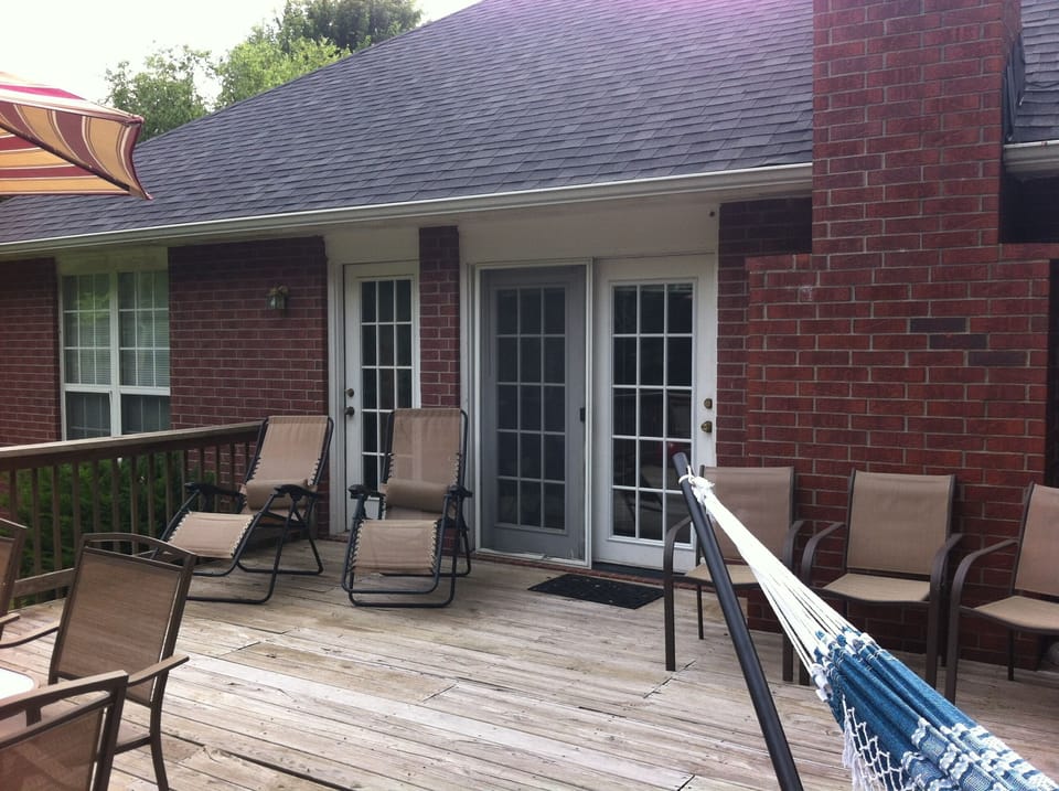 Back of house features deck and wooded yard.  