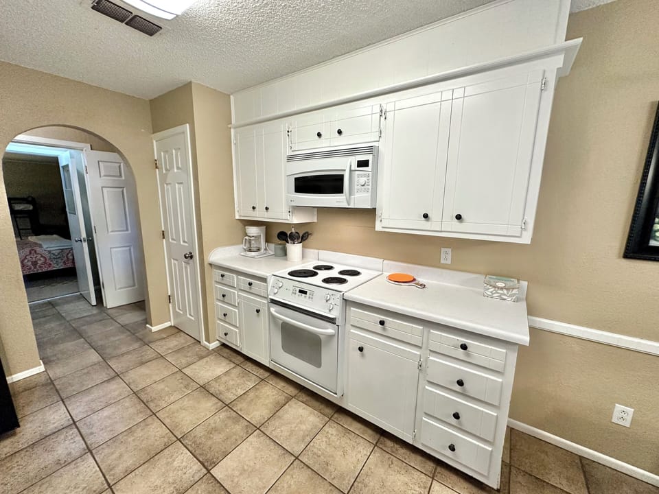 Pantry, coffee pot, electric stove and microwave.