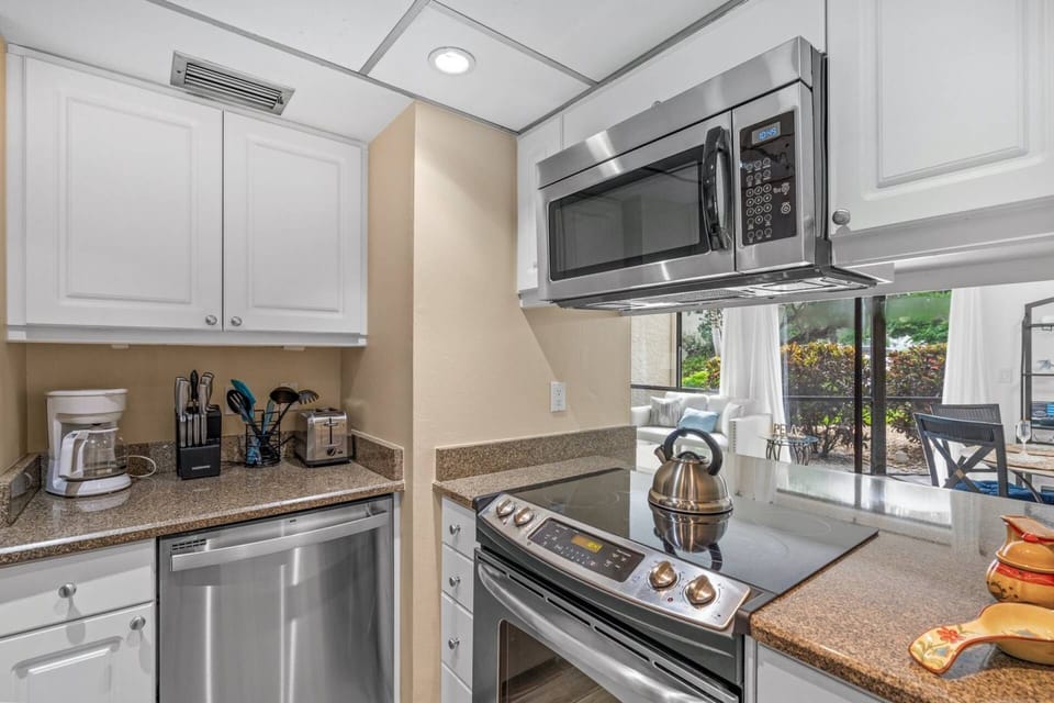 Stainless oven/stove with black glass top and built-in microwave with opening to the bar seats and dining area.
