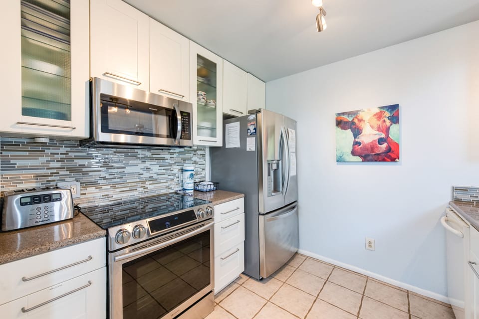 Prepare your favorite meals in this sleek, fully-equipped kitchen featuring modern stainless steel appliances and stylish tile backsplash.