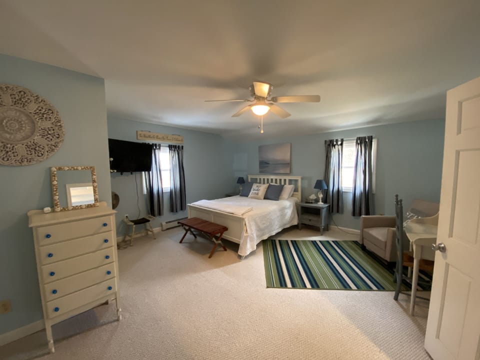 Spacious Master Bedroom with tv, chair and desk and air conditioner in summer.